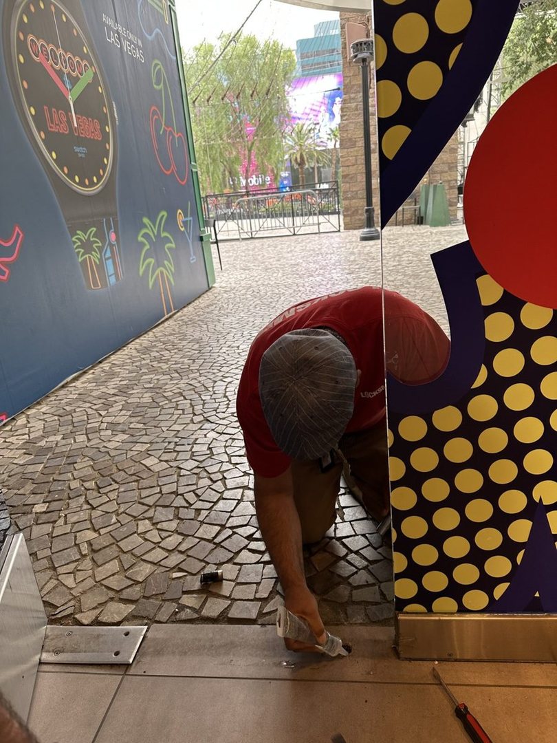 A Silver State Locksmith tech bent over the base of a storefront door on the Las Vegas Strip
