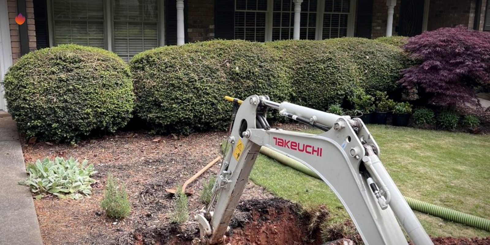 A mini excavator digging in a front yard for a septic repair