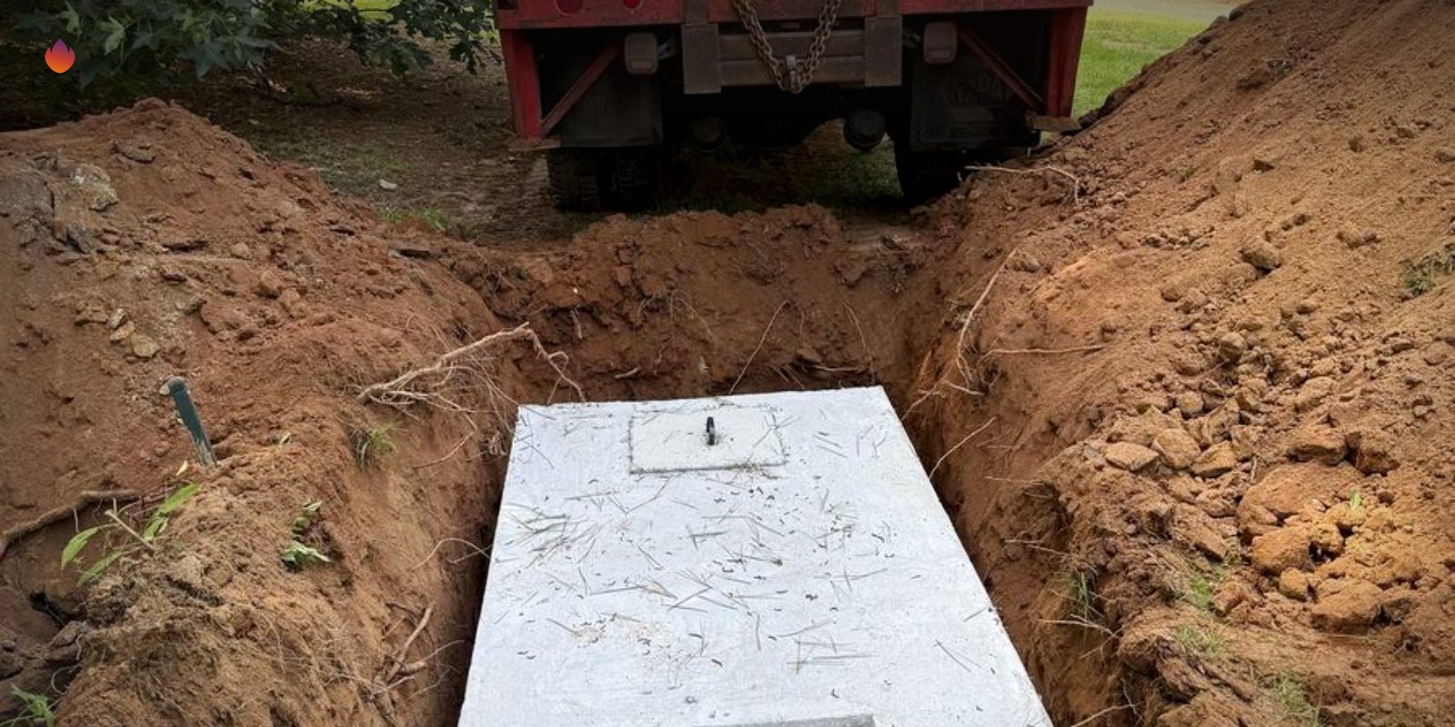 A new septic tank set in a trench with a skid steer behind it