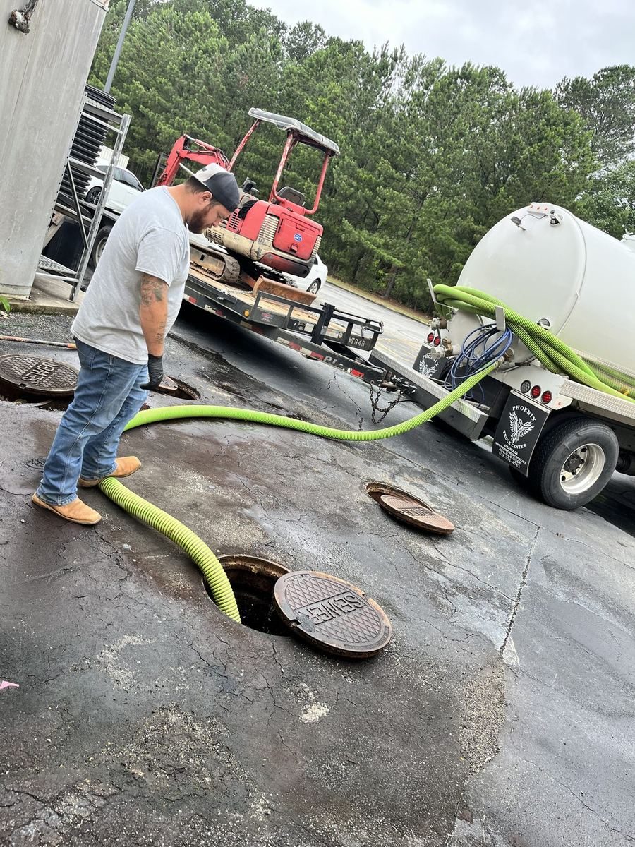 An Emergency Septic & Sewer tech running a pumpout hose from the vacuum truck to an open tank lid