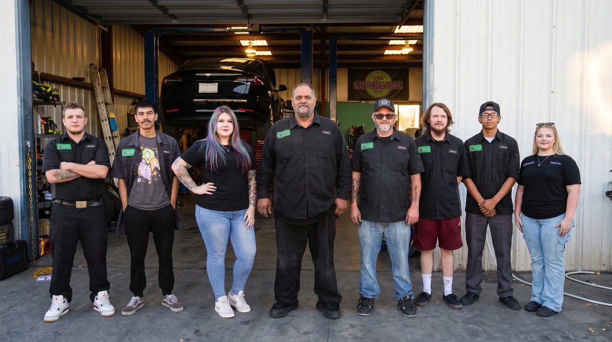 The Supercanic crew lined up in front of the open bays at the shop