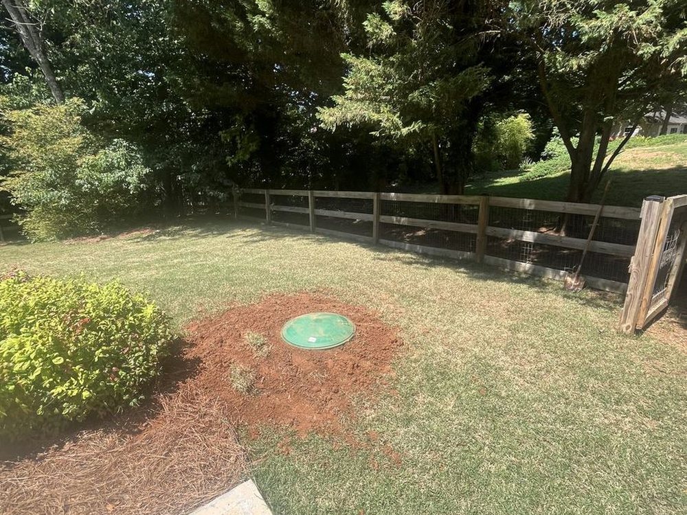 A green septic riser lid set flush in a freshly restored lawn