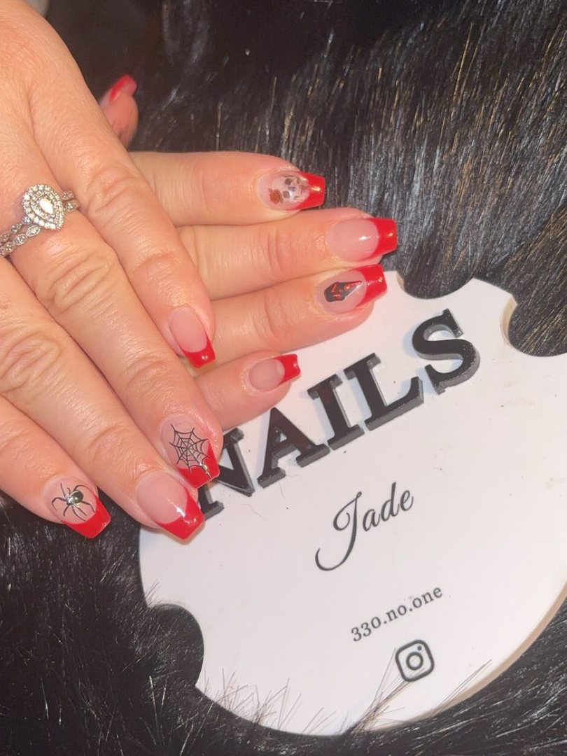A set of red French tip nails with a spiderweb design