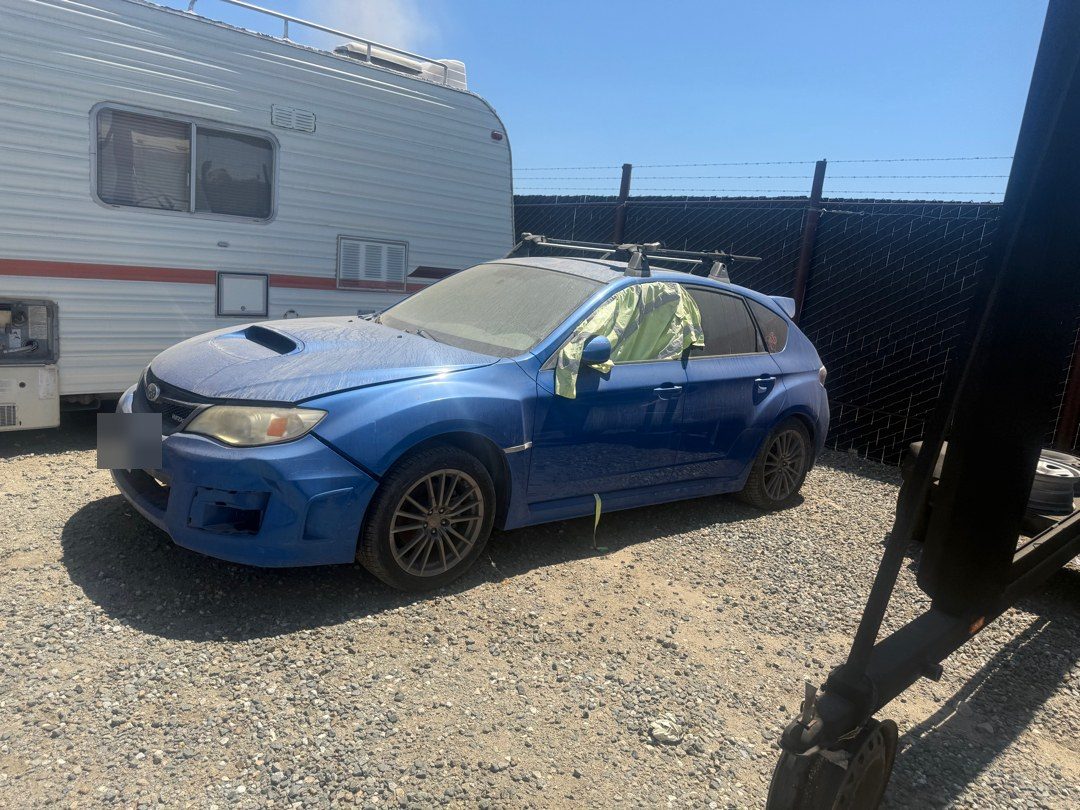 A blue Subaru WRX hatchback on a gravel lot waiting for a pre purchase inspection