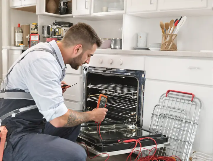 Tech testing an oven bake element with a meter