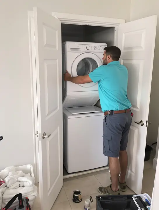 Tech sliding a stacked washer out of a condo laundry closet in Fort Lauderdale