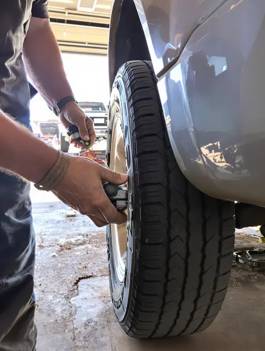 Mechanic checking tire tread on a pickup in a West Texas shop