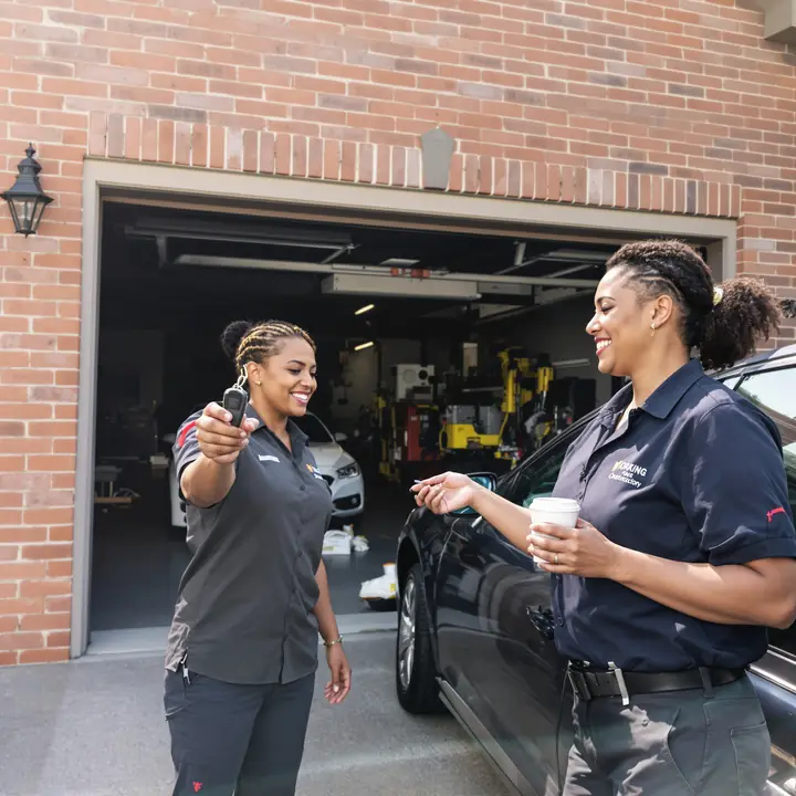 Homeowner handing her keys to a Porchside mechanic outside her garage