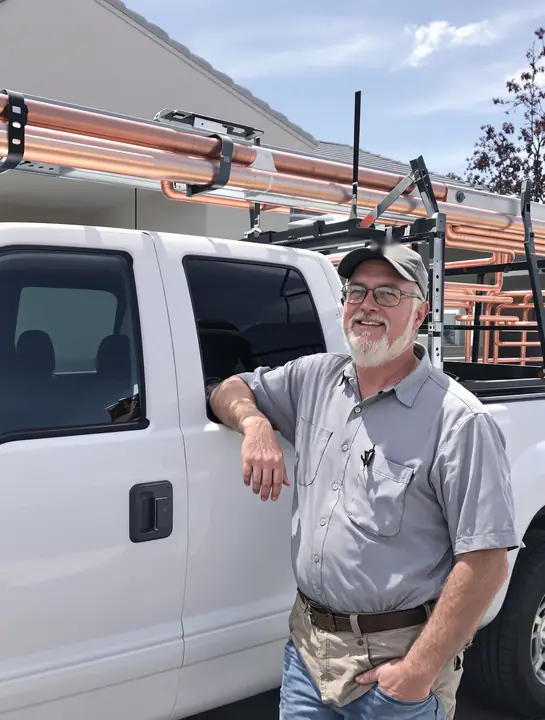 A plumber leaning on his work pickup in a Grand Junction neighborhood