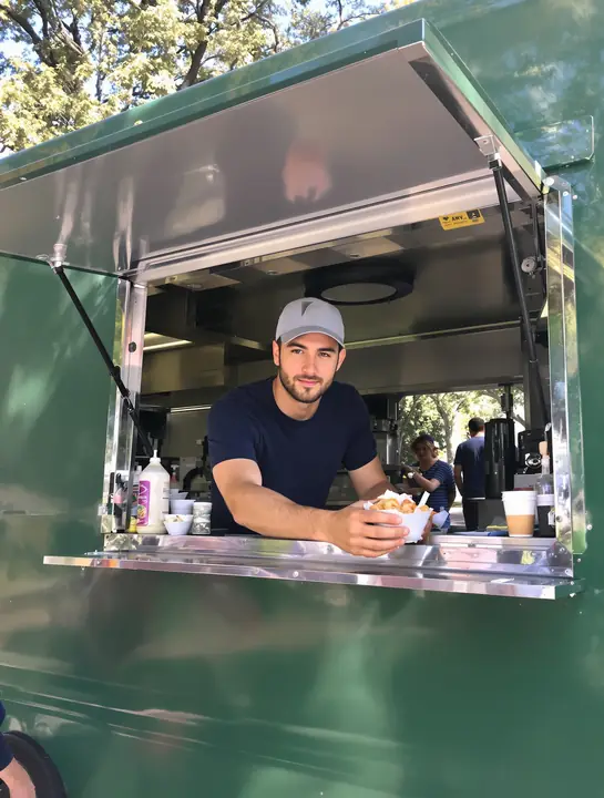 Food truck owner serving a customer near campus