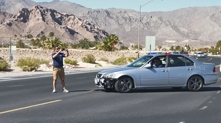 Driver taking photos of a damaged car on the shoulder of a Las Vegas road