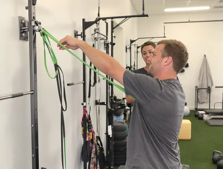 Patient doing a band exercise on the rehab floor while the chiropractor watches
