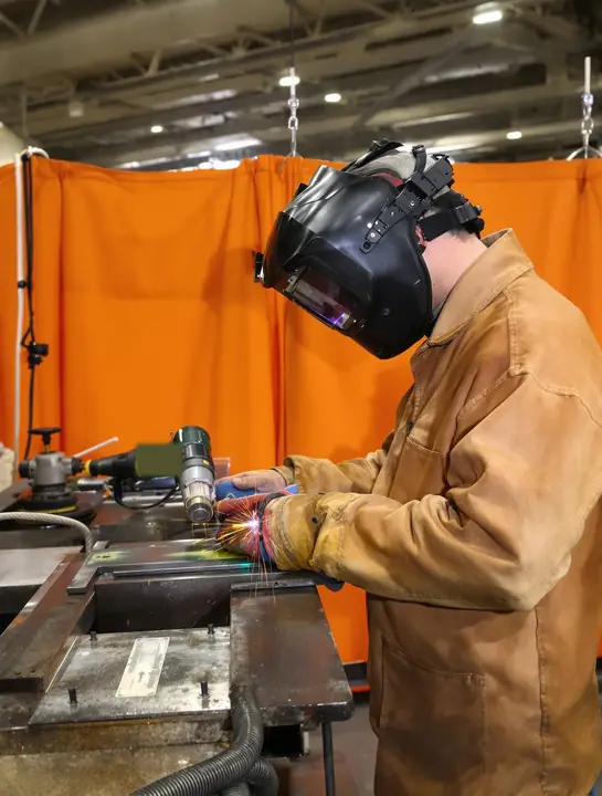 Welding student checks a T joint in the welding booth