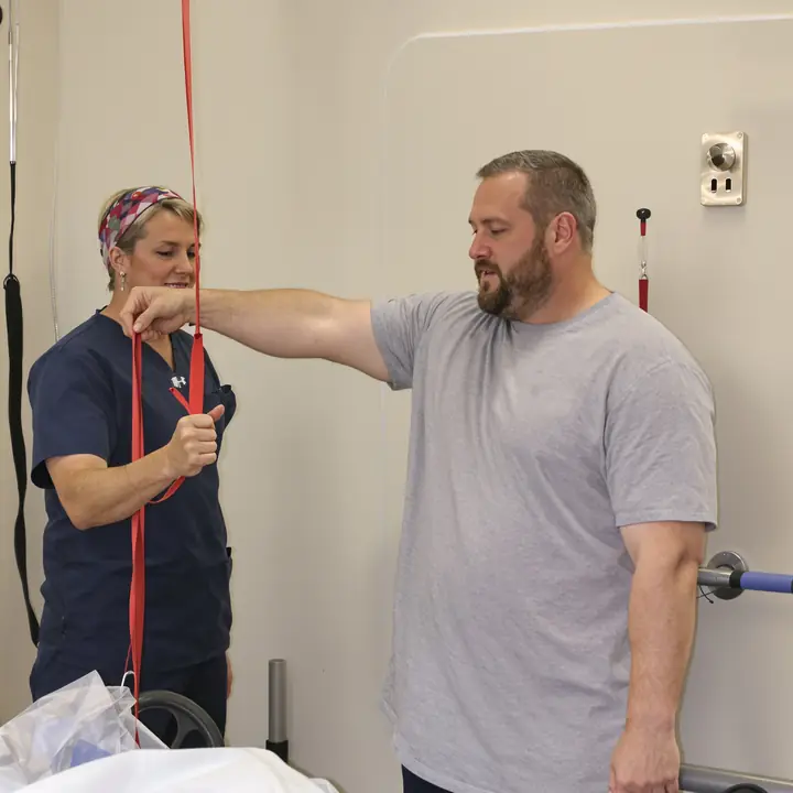 Physical therapist working a shoulder exercise with an injured worker