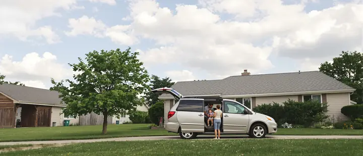 Young family loading a toddler into a minivan in a Derby driveway