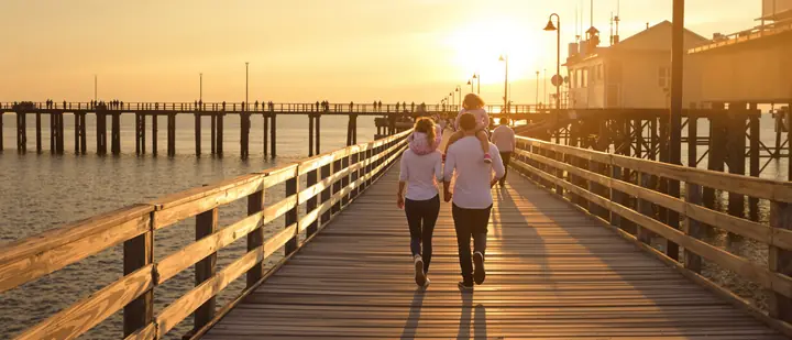 A young family walking out on a fishing pier on Mobile Bay at sunset