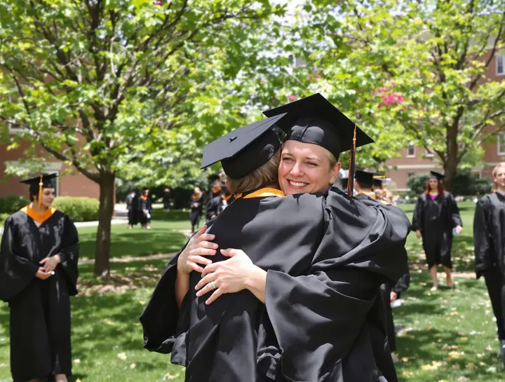 A graduate hugging her son on the lawn after commencement