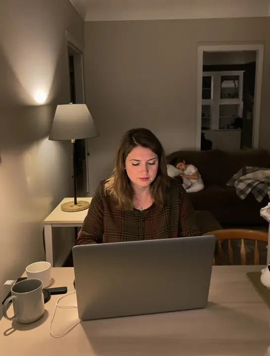 A parent doing coursework at the kitchen table late at night