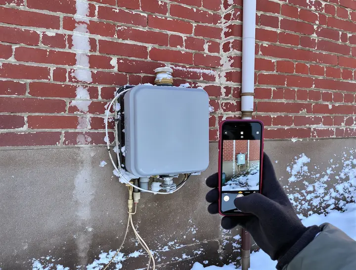 Taking a photo of a snowy gas meter on a brick house