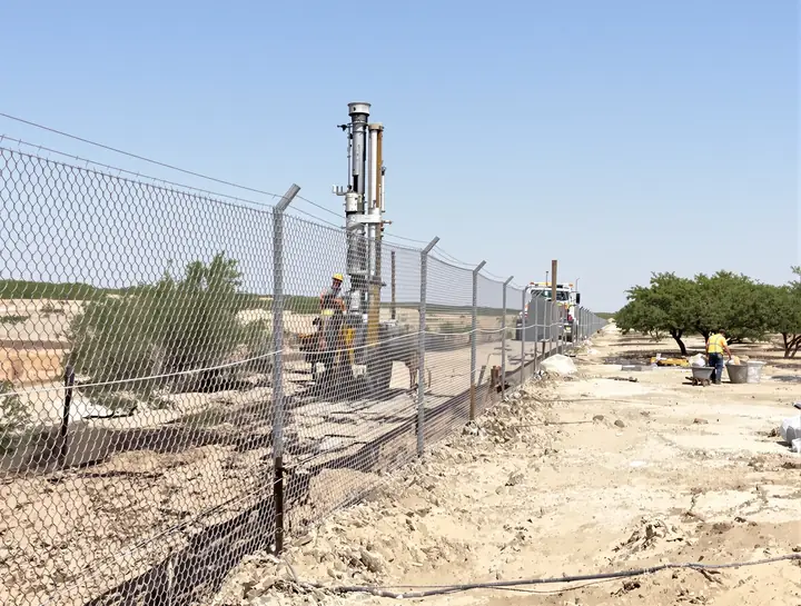 Crew setting galvanized line posts along a new perimeter in Robstown