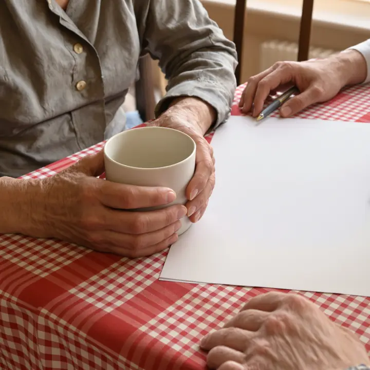 A client holding a coffee mug beside a blank form on a checked tablecloth