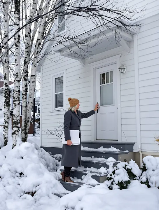 Karin at the door of a client's house on a snowy Duluth hillside