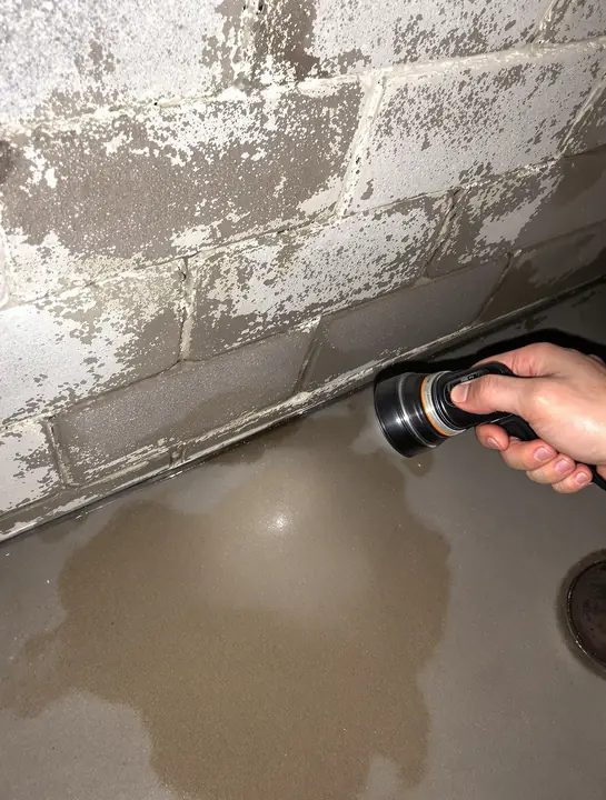 Damp stain and white chalk at the base of a block wall