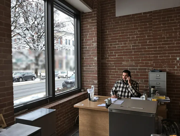 Loan officer on the phone at a wooden desk in a brick office downtown