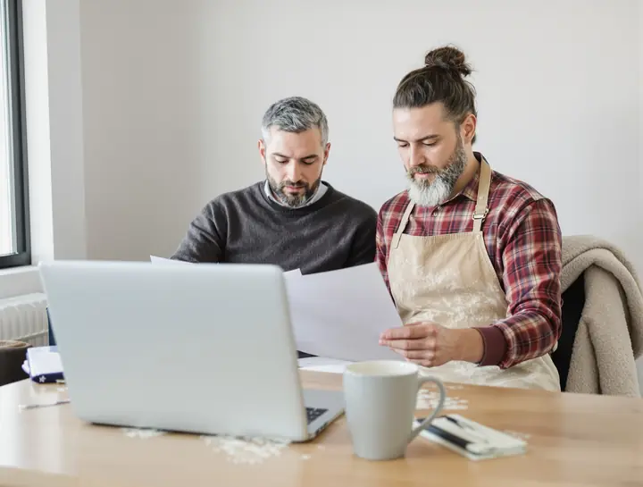 Loan officer and a bakery owner going over bank statements at a wooden table
