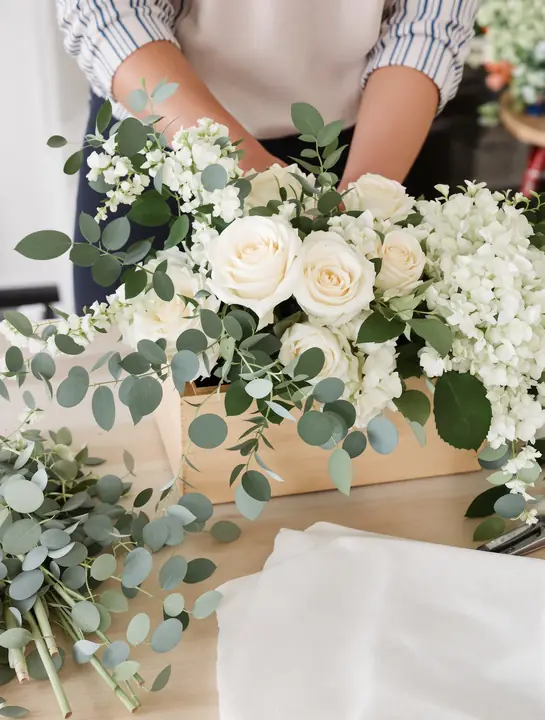 White roses and eucalyptus being arranged for a service