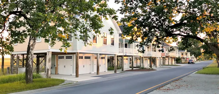 Raised coastal homes with garage doors under them near a marsh