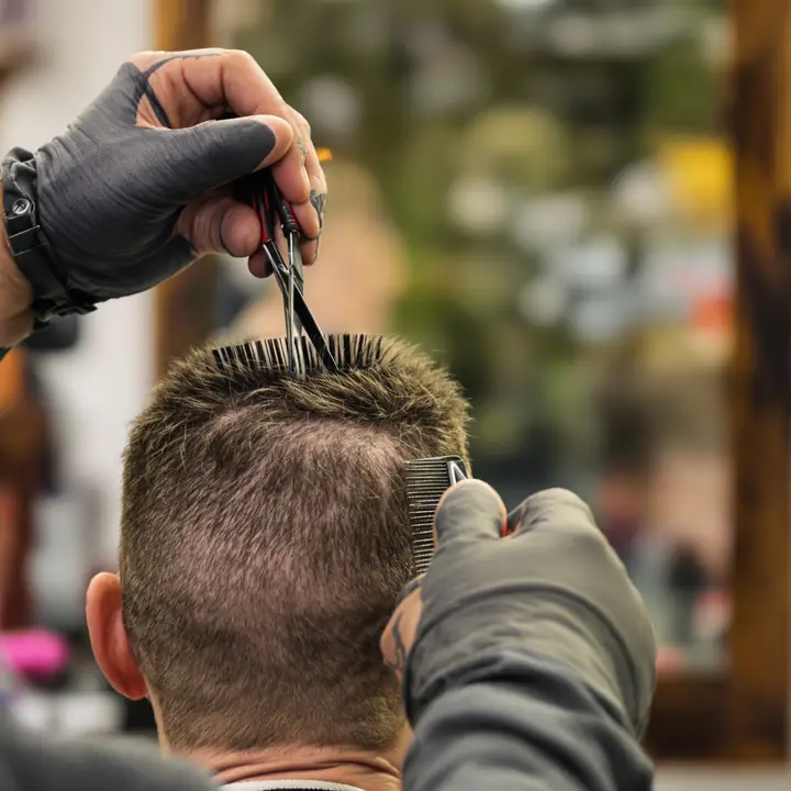 A barber trimming short hair on top