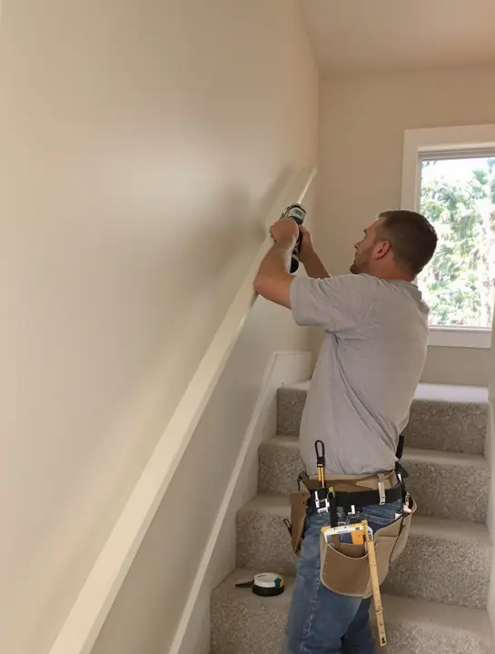 Installer mounting a second handrail on a short staircase