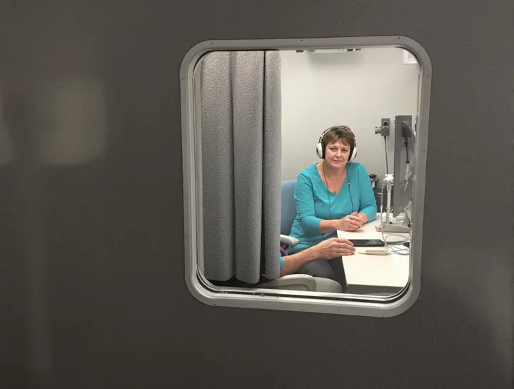 Patient wearing headphones in a sound booth