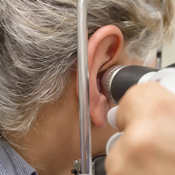 Audiologist looking into an ear with an otoscope