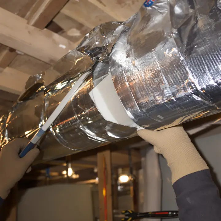 Installer sealing a sheet metal duct joint with mastic