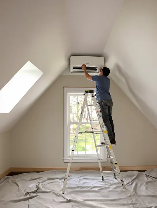 Tech mounting a ductless mini split in an attic bedroom