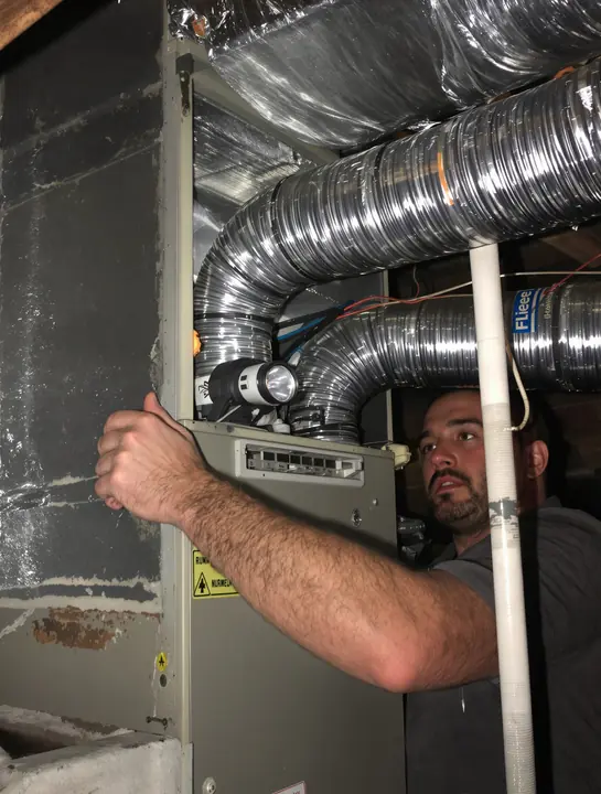 Tech working on an air handler in a hot attic