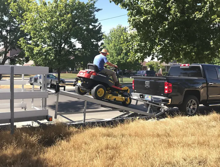 Landscaper driving a mower up onto a trailer