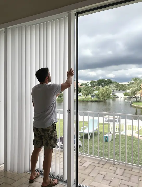Homeowner closing hurricane shutters on a lanai as a storm builds