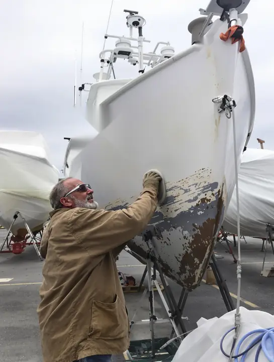 A boatyard owner sanding a hull on Narragansett Bay