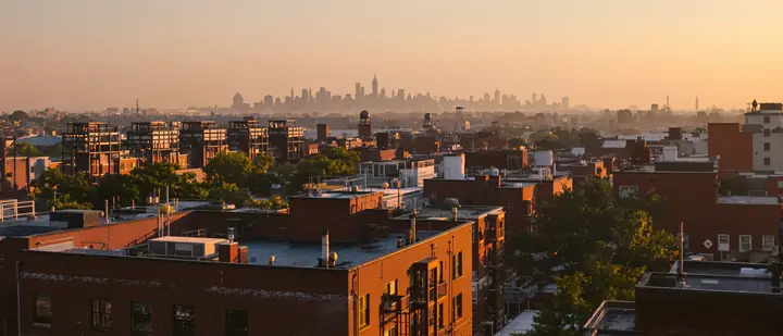 Rooftops and water towers of Astoria at sunset with Manhattan far behind