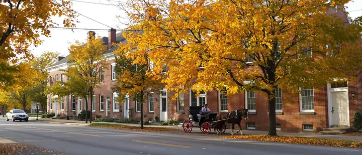 Brick row houses in downtown Lancaster with a horse drawn buggy passing in the fall