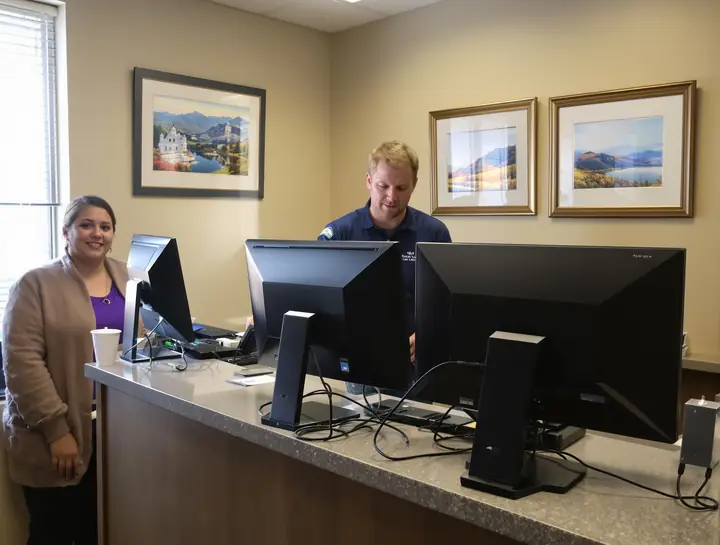 Tech setting up new monitors at the front desk of an Orem law office