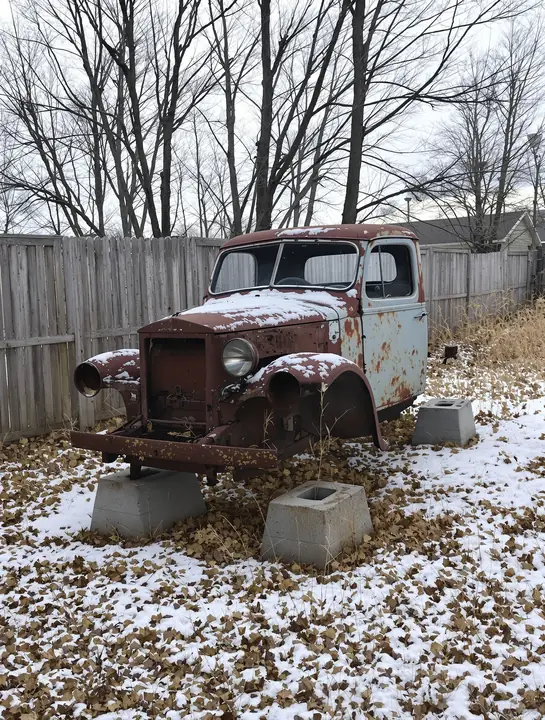 Old truck with no wheels sitting on cinder blocks in the snow