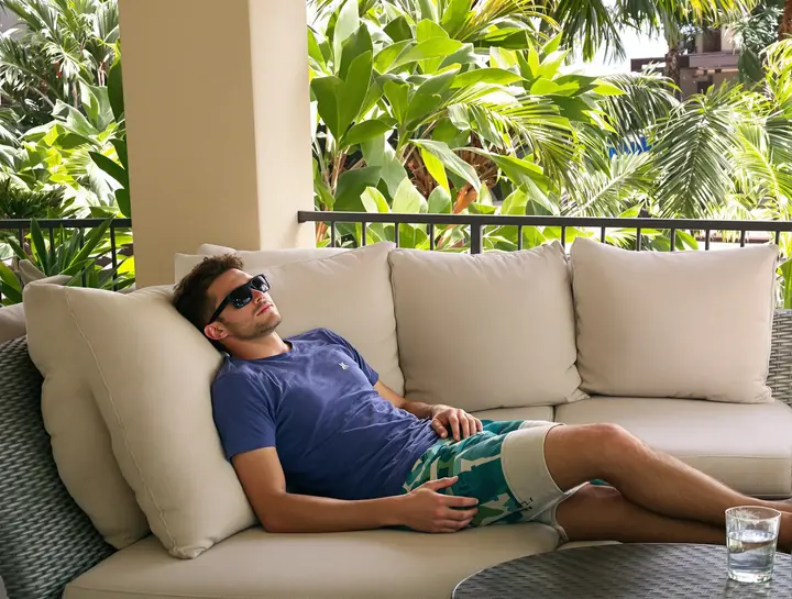 A patient resting on his shaded lanai in dark sunglasses the day after surgery