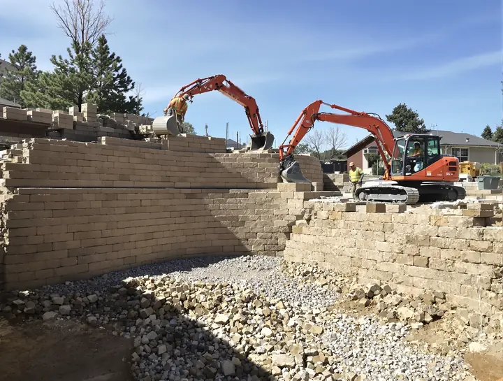 Crew setting stacked stone blocks for a curved retaining wall