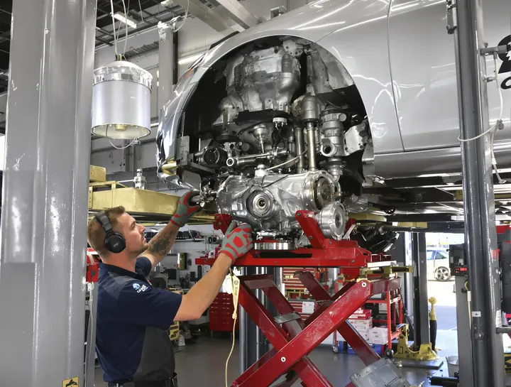 A tech lowering a transmission out of a nearly new car