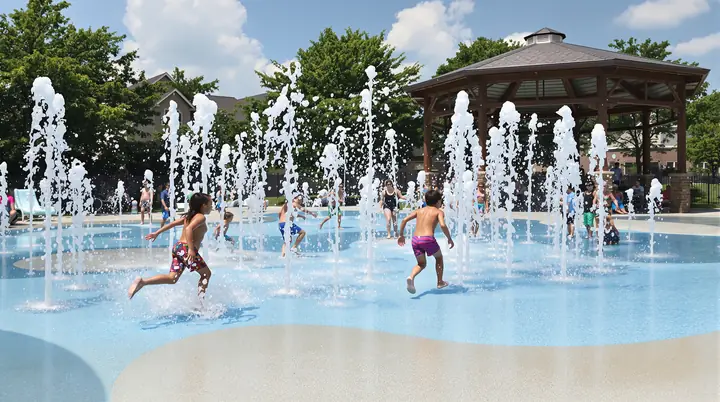 Kids running through a splash pad at a Frisco park