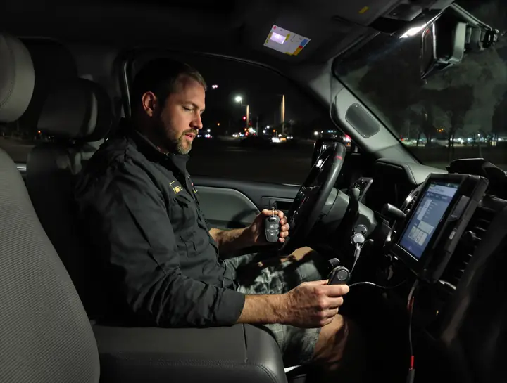 Locksmith programming a new key fob in a pickup at night
